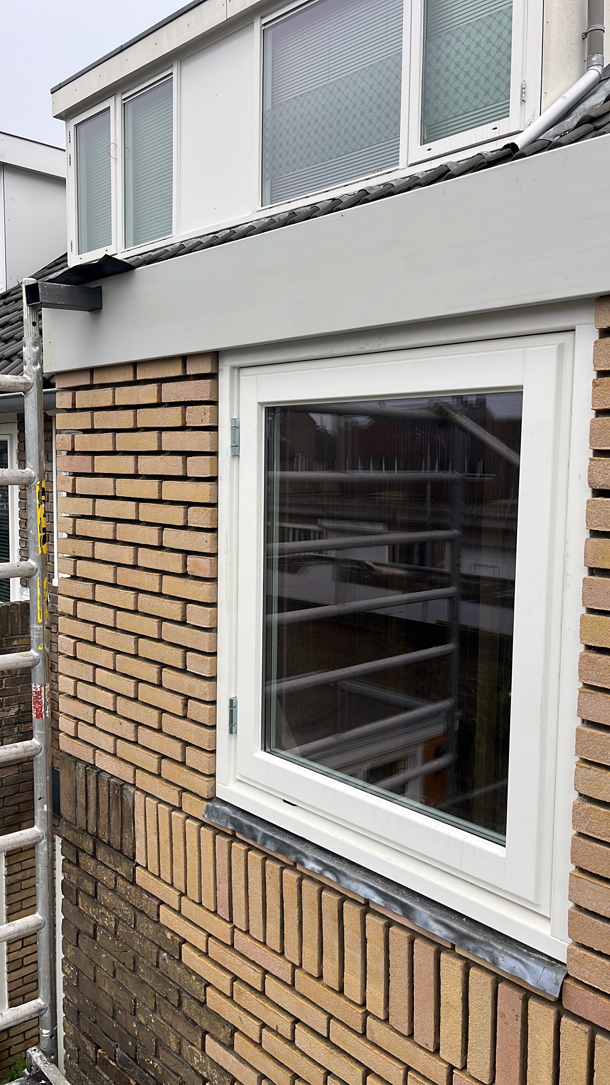 Afgewerkt metselwerk rondom een wit kozijn met loodslabbe, dakkapel erboven