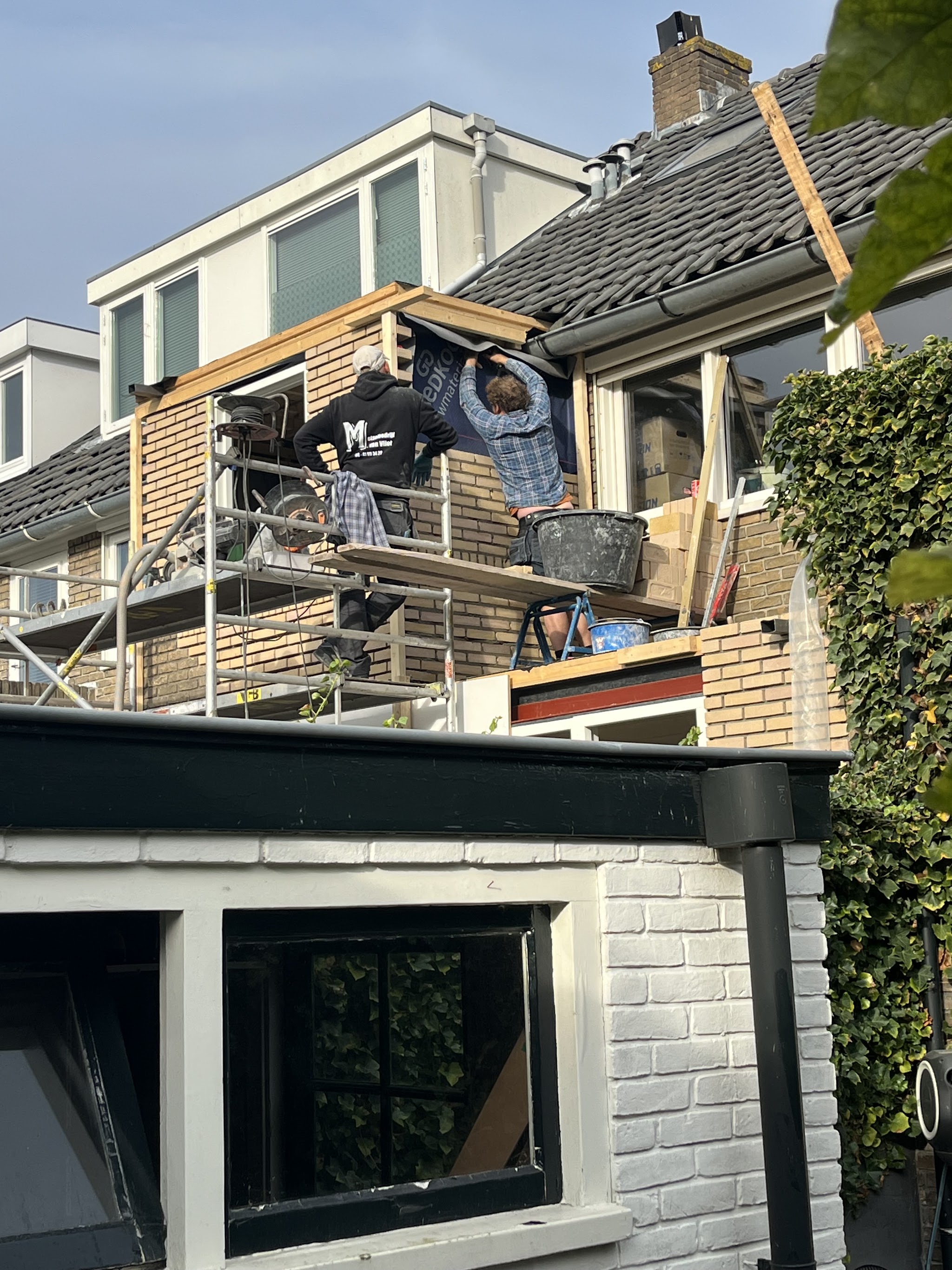 Twee mannen op de steiger bij het houten frame van de dakopbouw
